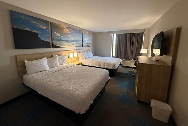 A hotel room with two beds, a desk, a TV, and artwork on the wall. - Days Inn by Wyndham Amarillo East (Amarillo)