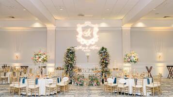 A banquet hall with round tables, gold chairs, and floral centerpieces.