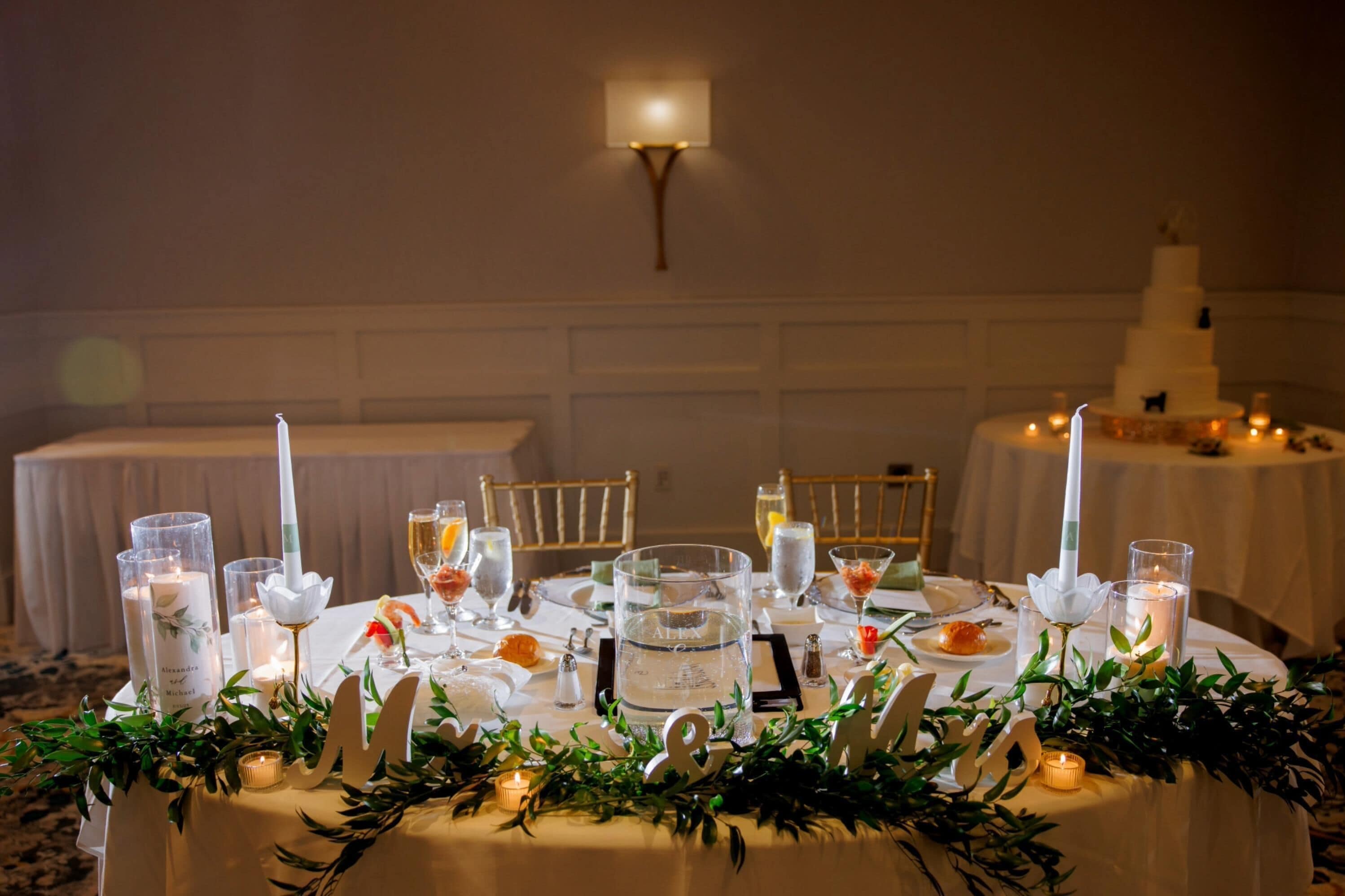 A round table set for a formal event with candles, glassware, and floral decorations.