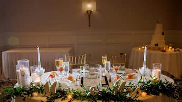 A round table set for a formal event with candles, glassware, and floral decorations.