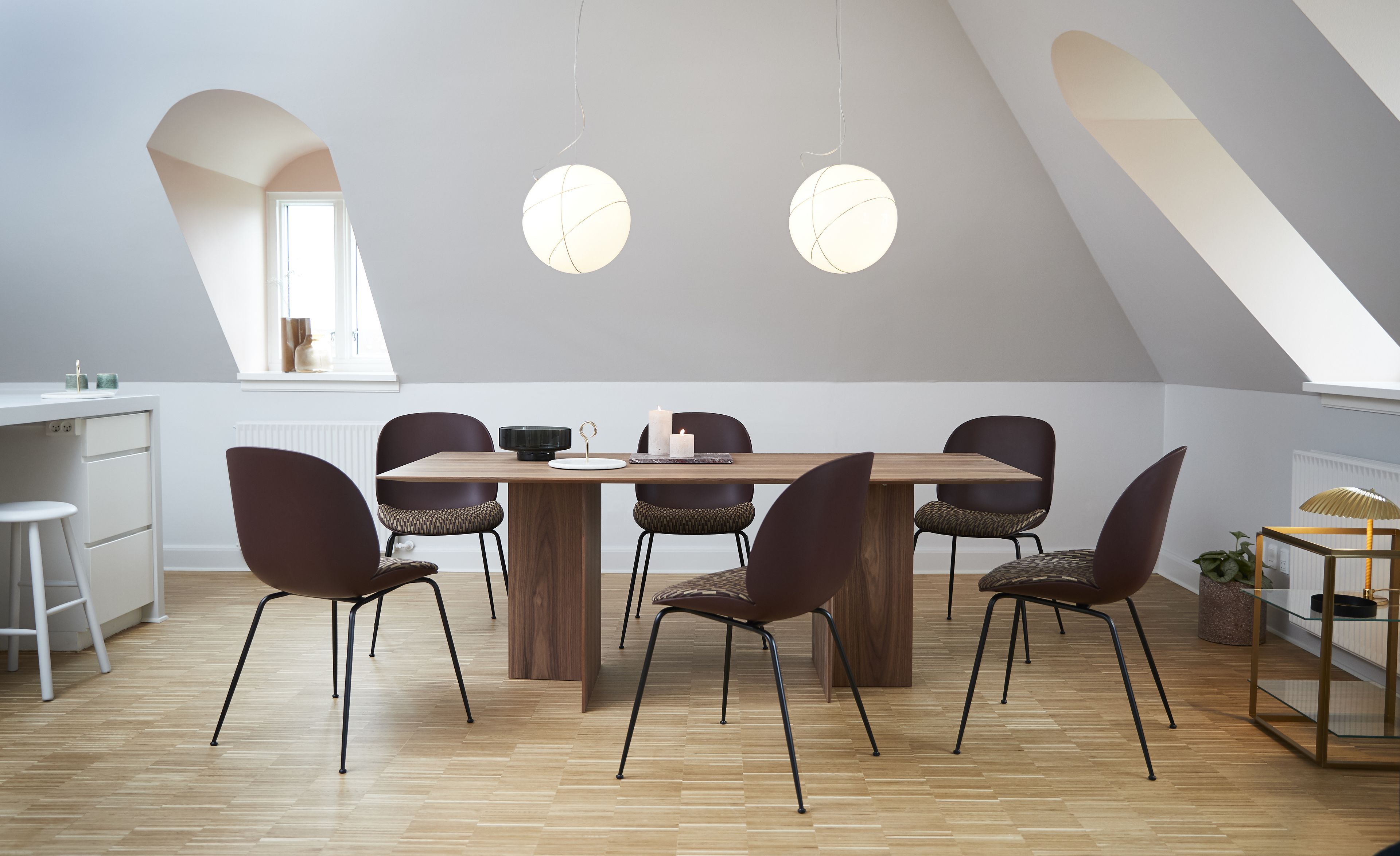 A modern dining area with a wooden table, six chairs, and two pendant lights.