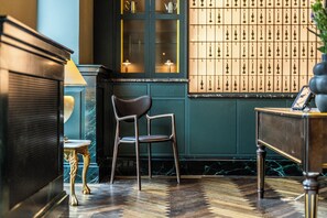 A room with a wooden floor, a chair, a table, and a cabinet with a lamp.