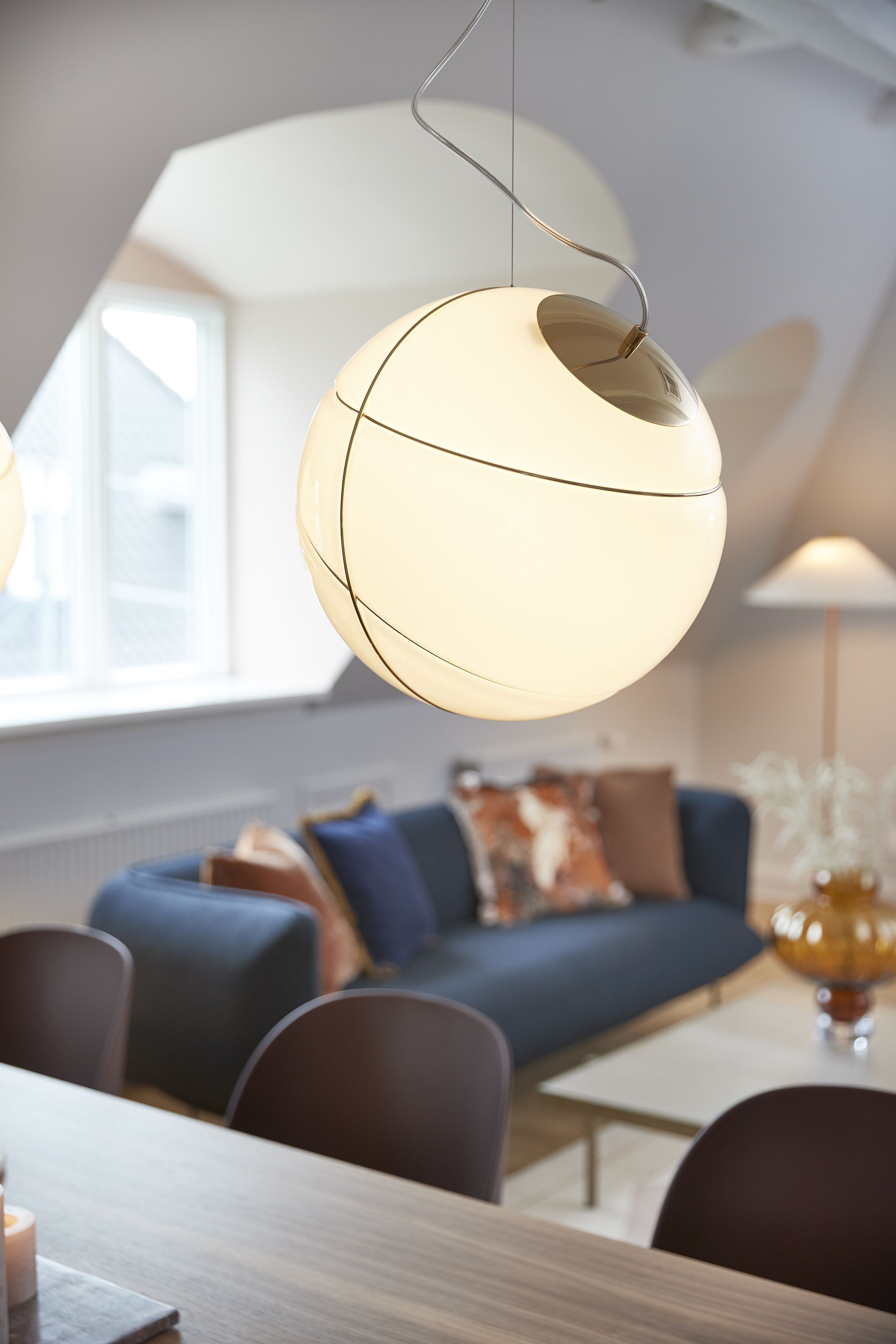 Et moderne spiseområde med et rundt bord, stole og en hængende lampe.