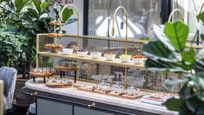 Un buffet avec plusieurs points de service, proposant une variété de plats et de desserts, le tout mis en valeur par un décor composé de plantes d'intérieur et d'un mur à motifs.