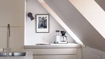 A modern kitchen with white cabinetry, a coffee machine, and a pendant light.