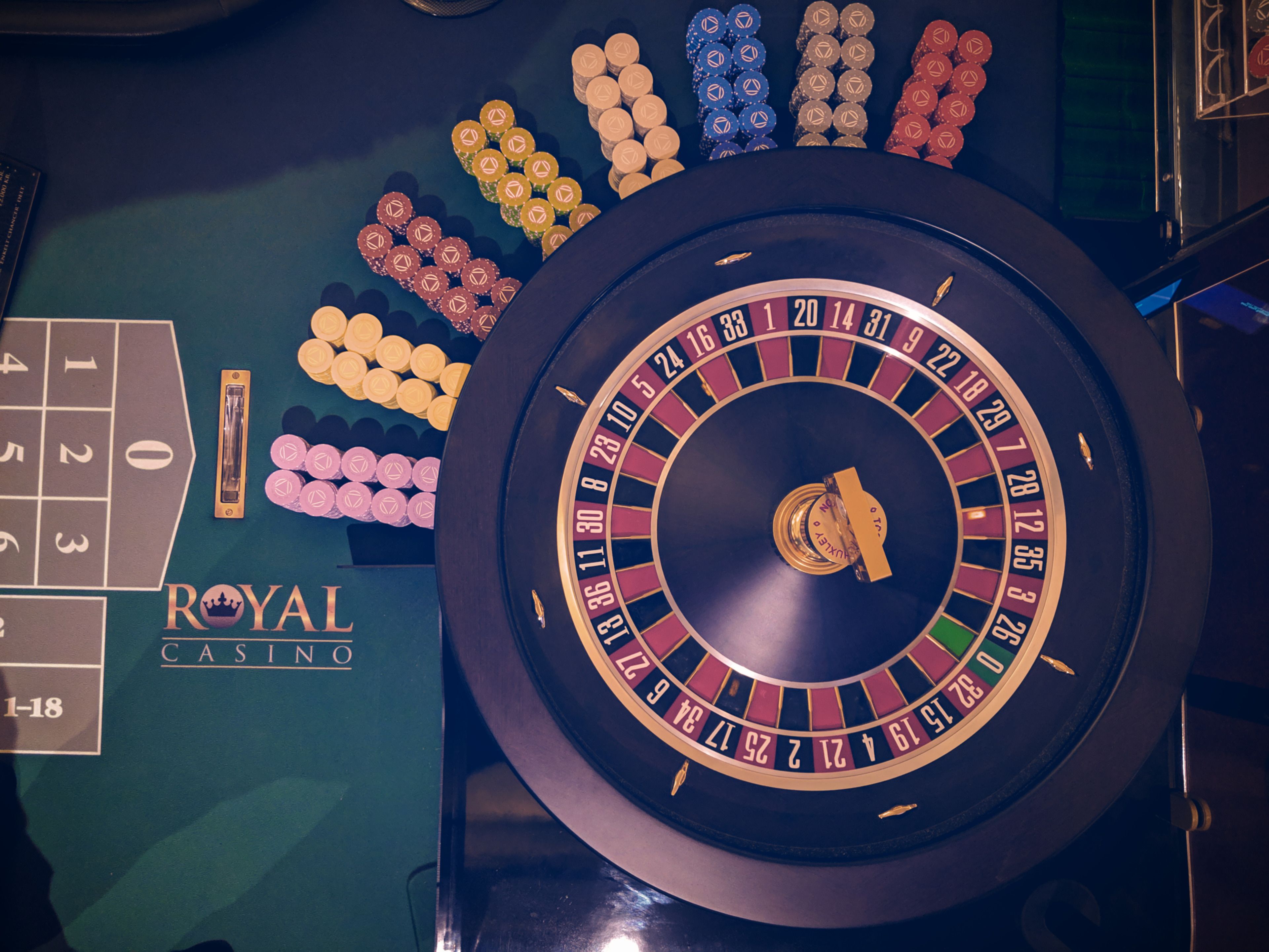A roulette wheel and chips on a casino table.