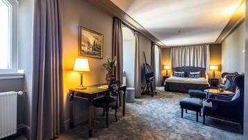 A hotel room with a bed, desk, chair, and a view of the city.