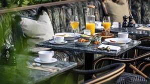 Une table à manger avec des aliments pour le petit-déjeuner, notamment des assiettes, des verres et une bouteille de jus d’orange.