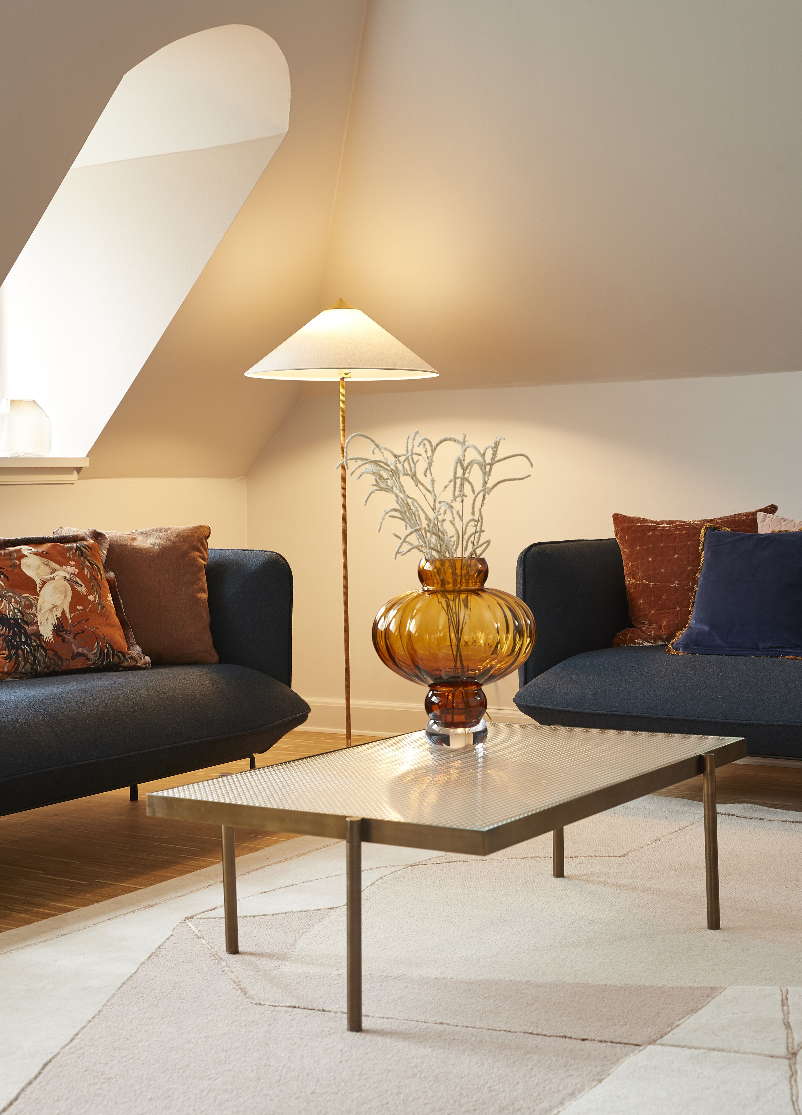 A modern living room with two sofas, a coffee table, a floor lamp, and a decorative vase.