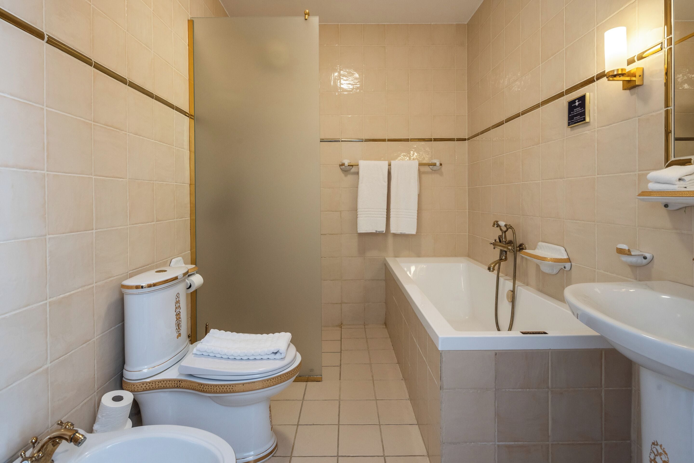 Un baño con inodoro, bidé, bañera y lavamanos.