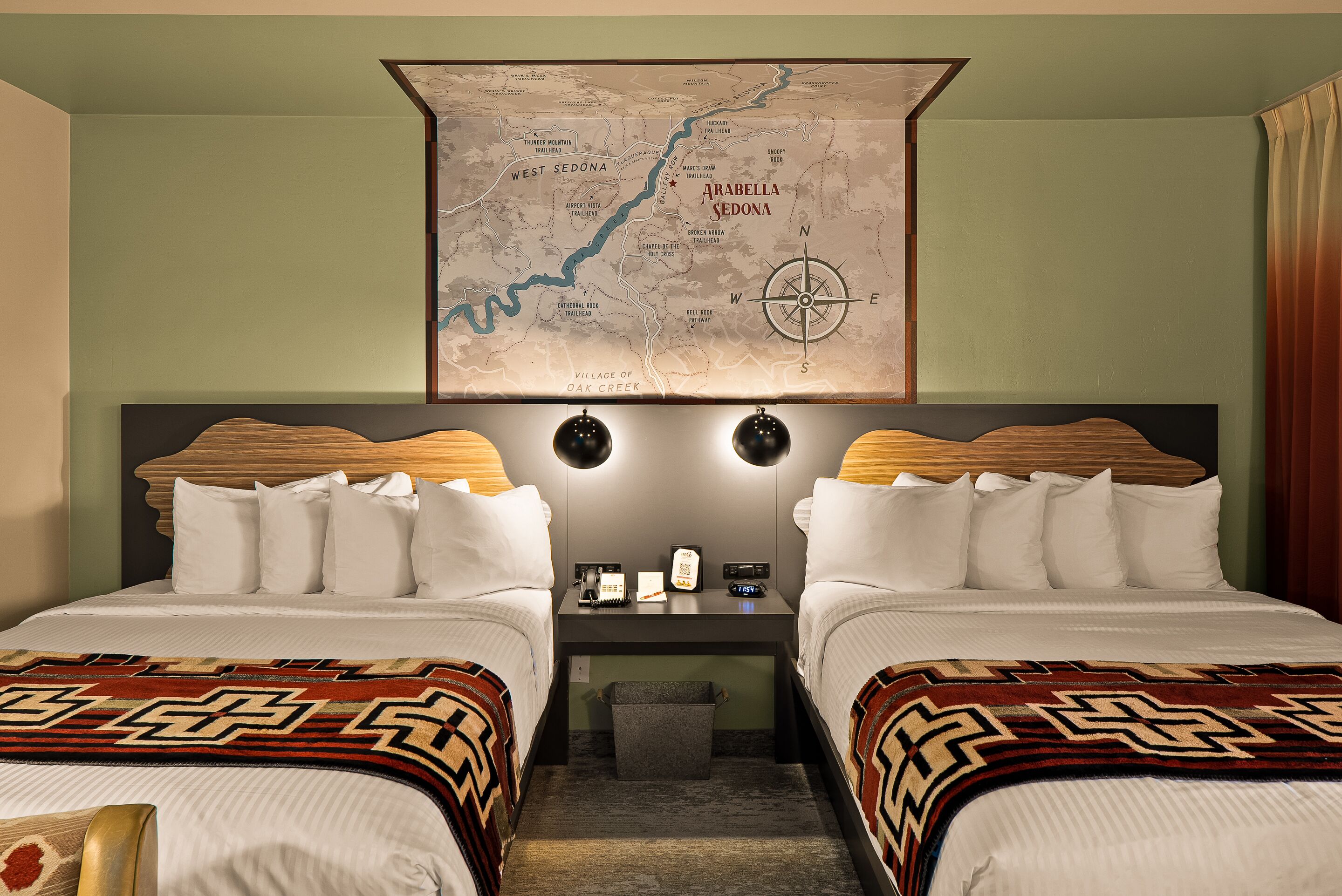 Habitación de hotel con dos camas, un escritorio y un mapa en la pared.
