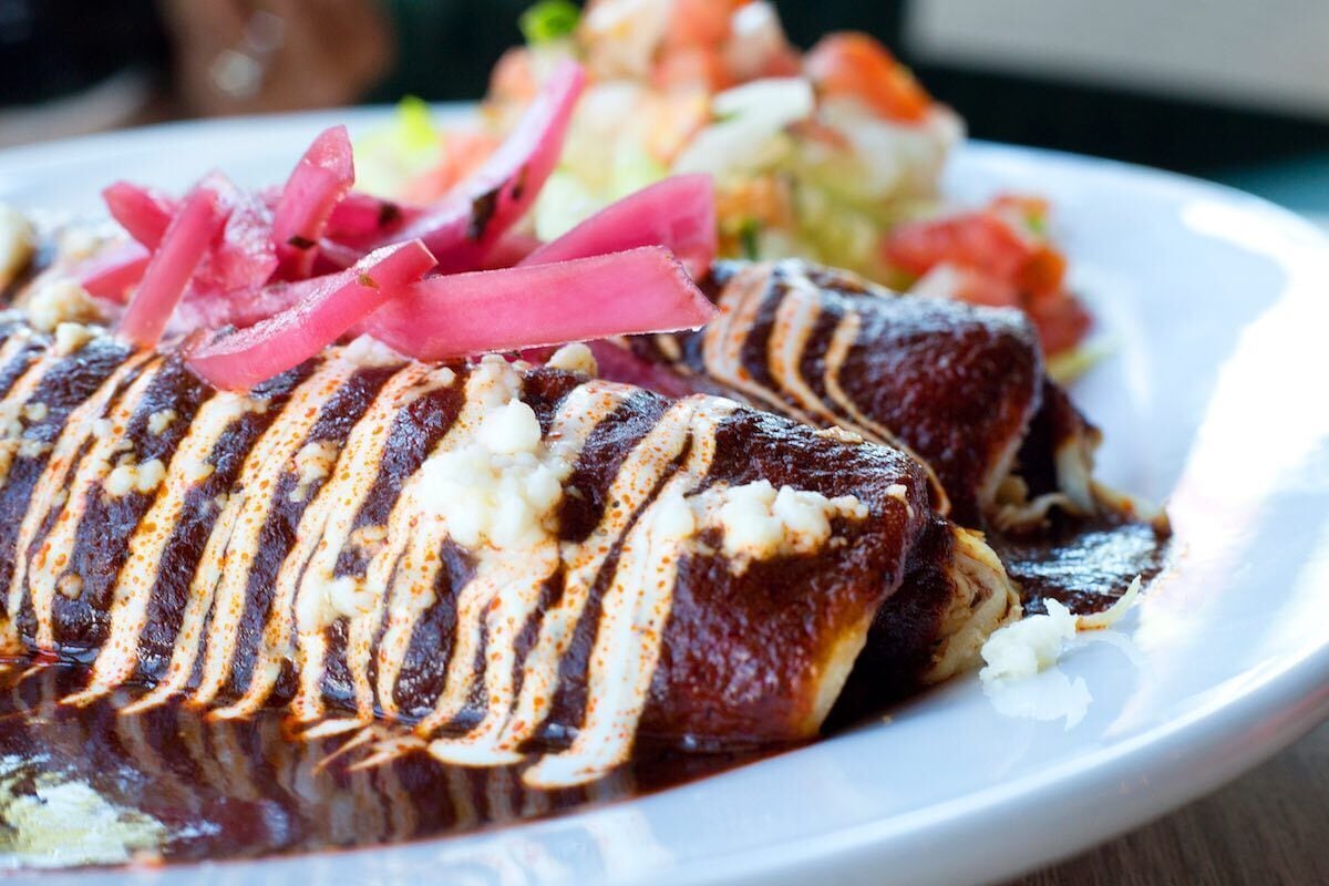 Un plato con carne a la parrilla, posiblemente filete, adornado con salsa y vegetales encurtidos.