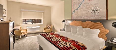 A hotel room with a large bed, a desk, a chair, a map on the wall, and a window with blinds.