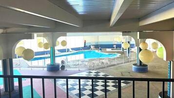 A pool area with a checkered floor, lounge chairs, and a view of the pool through a glass barrier.