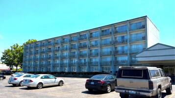 A multi-story hotel with a parking lot in front.