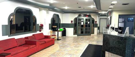 A reception area with a red sofa, a reception desk, and a door with a sign.