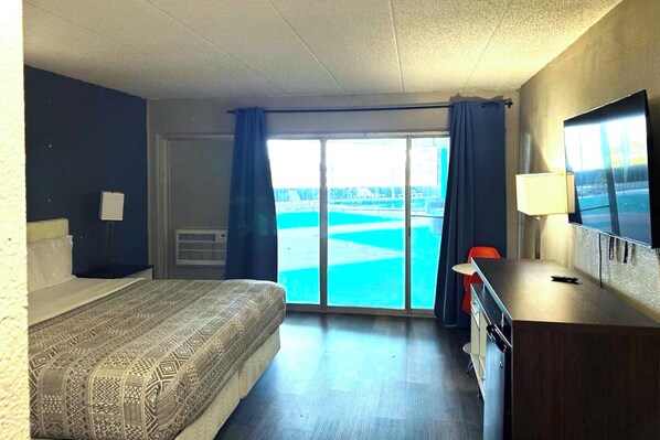 A hotel room with a bed, a desk, a television, and a view of a body of water through the window.
