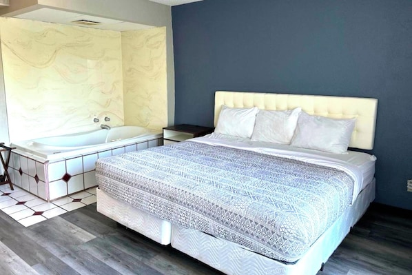 Un dormitorio con una cama grande, una mesita de noche y una bañera.