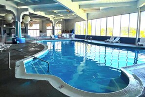 An indoor swimming pool with a diving board, lounge chairs, and large windows. - Twin City Inn & Suites Benton Harbor - St. Joseph (Benton Harbor)