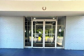 A building entrance with a glass door and a white brick wall. - Twin City Inn & Suites Benton Harbor - St. Joseph (Benton Harbor)