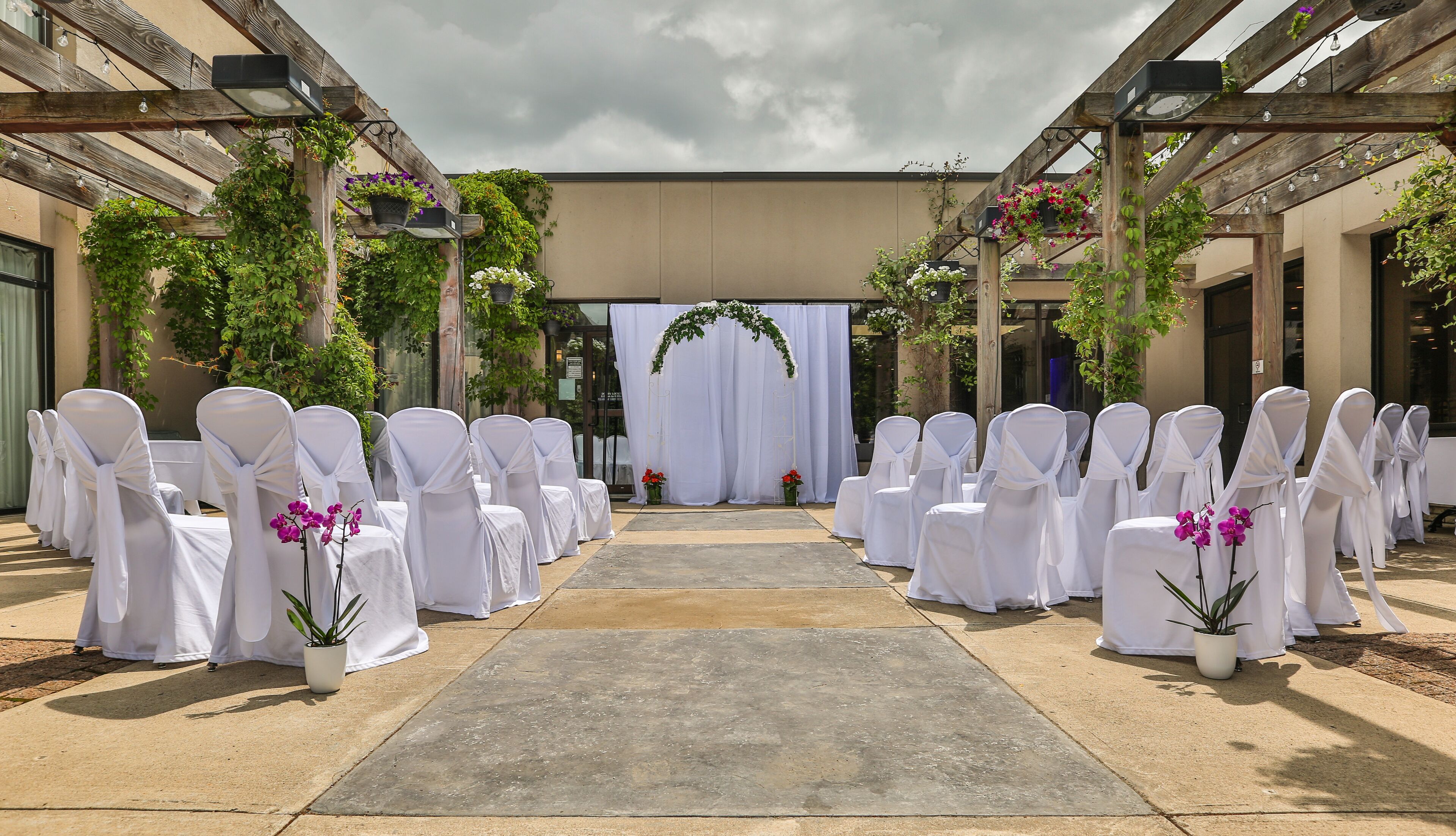 A wedding aisle with white chairs and floral decorations.