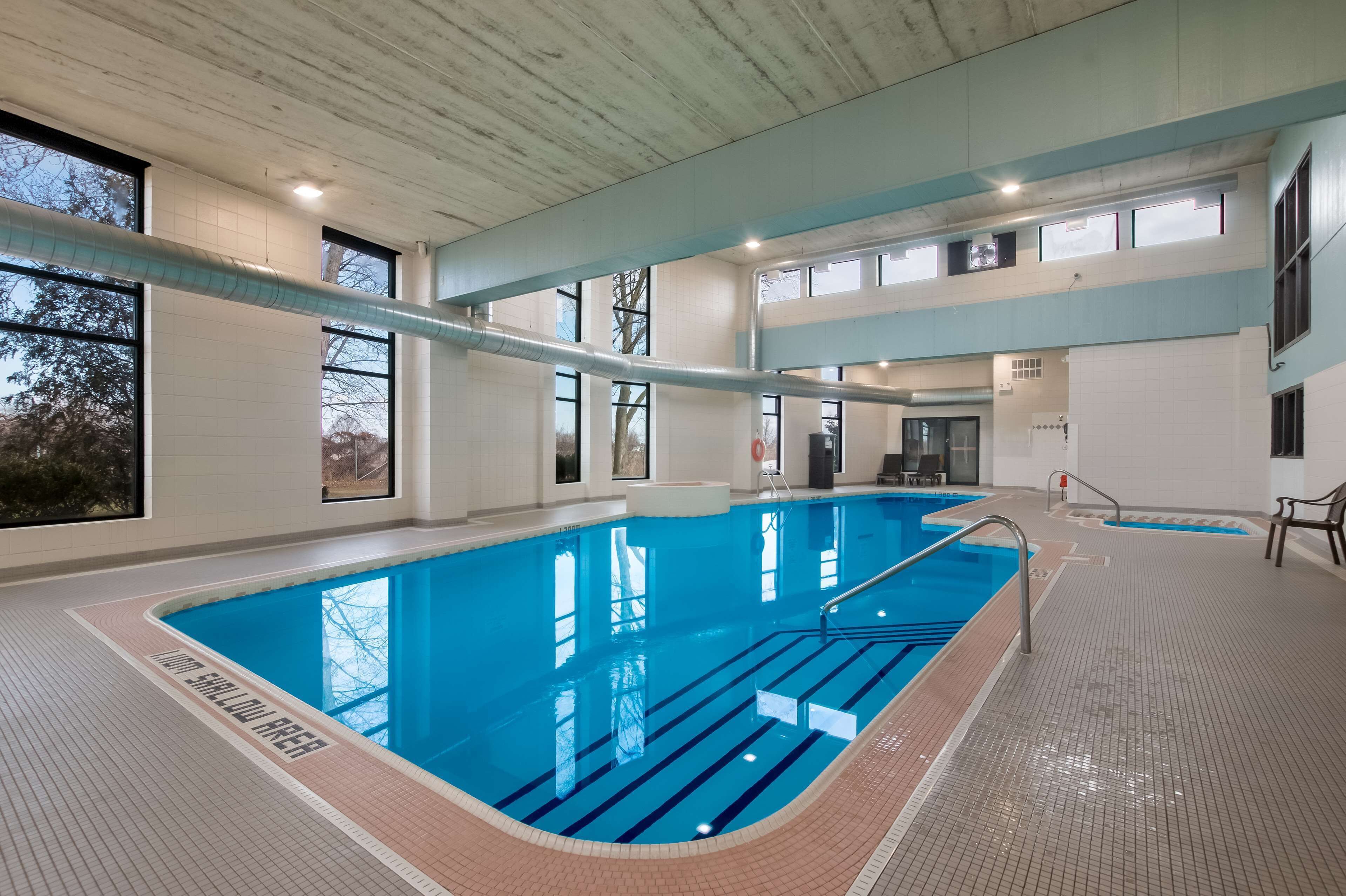 Una piscina interior con agua azul cristalina, paredes de azulejos y techo de madera.