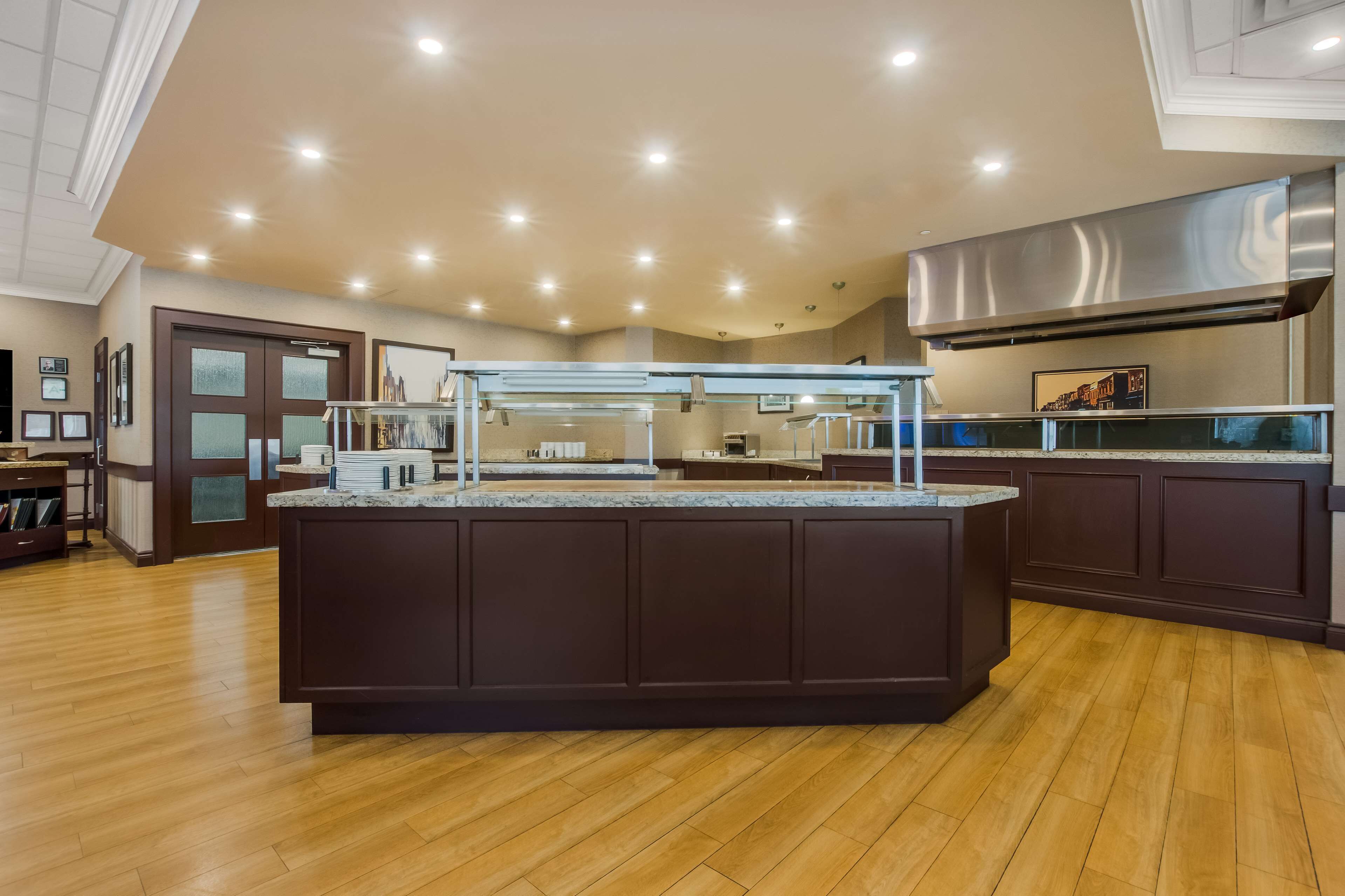 A modern kitchen with a central island, wooden flooring, and recessed ceiling lighting.