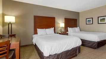 A hotel room with two beds, a desk, and a chair.
