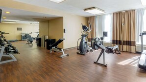 A gym with exercise equipment, a mirror, and a large window with curtains. - Comfort Inn Blacksburg University Area (Christiansburg)