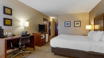 Ein Hotelzimmer mit Bett, Schreibtisch, Stuhl, Fernseher und zwei gerahmten Bildern an der Wand.