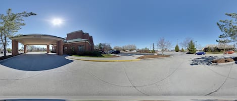 A parking area with a covered structure, a clear sky, and a few cars.