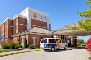 A Comfort Inn hotel with a brick facade, a van parked in front, and a clear blue sky. - Comfort Inn Blacksburg University Area (Christiansburg)