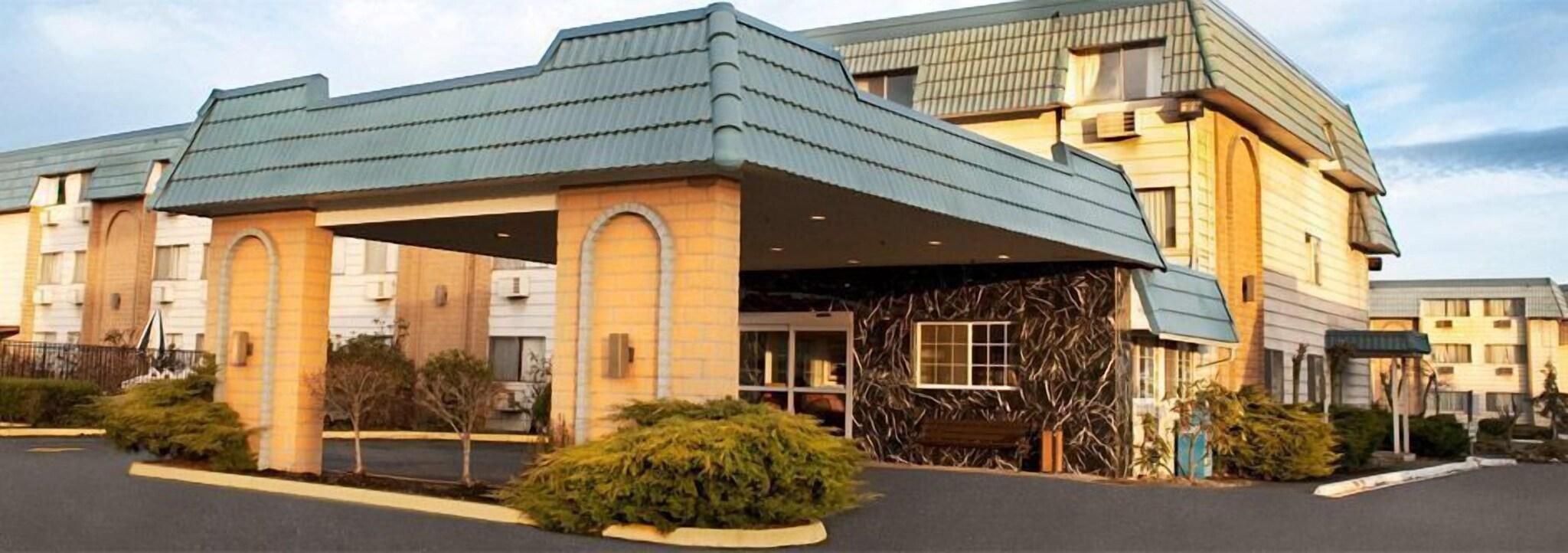 A hotel with a covered entrance, multiple windows, and a parking lot.
