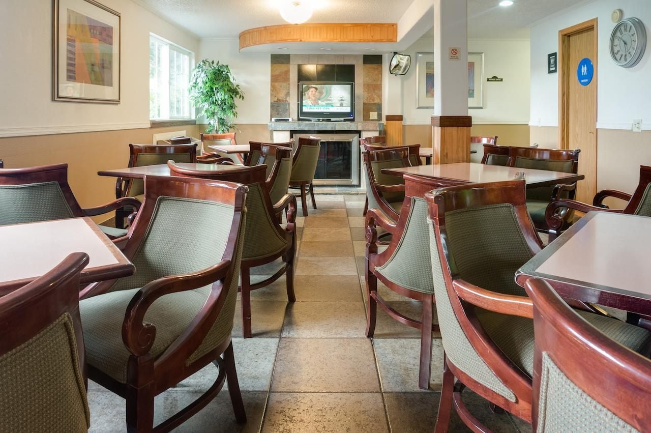A restaurant with wooden tables and chairs, a television, and a fireplace.