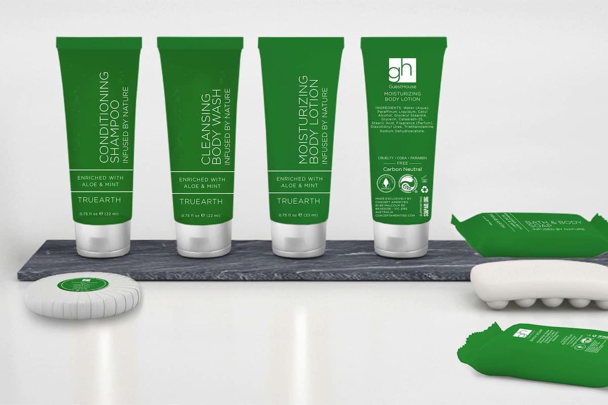 Quatre tubes verts de lotion pour le corps et un savon sur une surface en marbre.