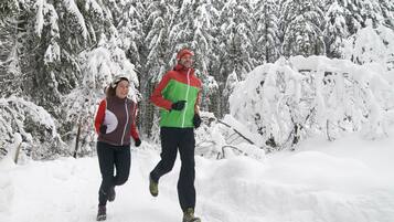 Two people running in a snowy forest.
