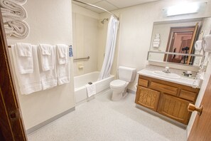 A bathroom with a bathtub, toilet, and sink. There are towels hanging on the wall. - Wedgewood Resort (Fairbanks)