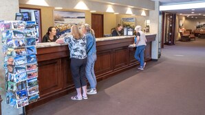 A reception area with a wooden counter, a bulletin board with postcards, and a seating area with chairs. - Wedgewood Resort (Fairbanks)