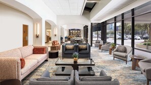 A spacious lobby with a sofa, armchairs, a coffee table, and a bar area in the background. - DoubleTree by Hilton Houston Medical Center Hotel & Suites (Houston)