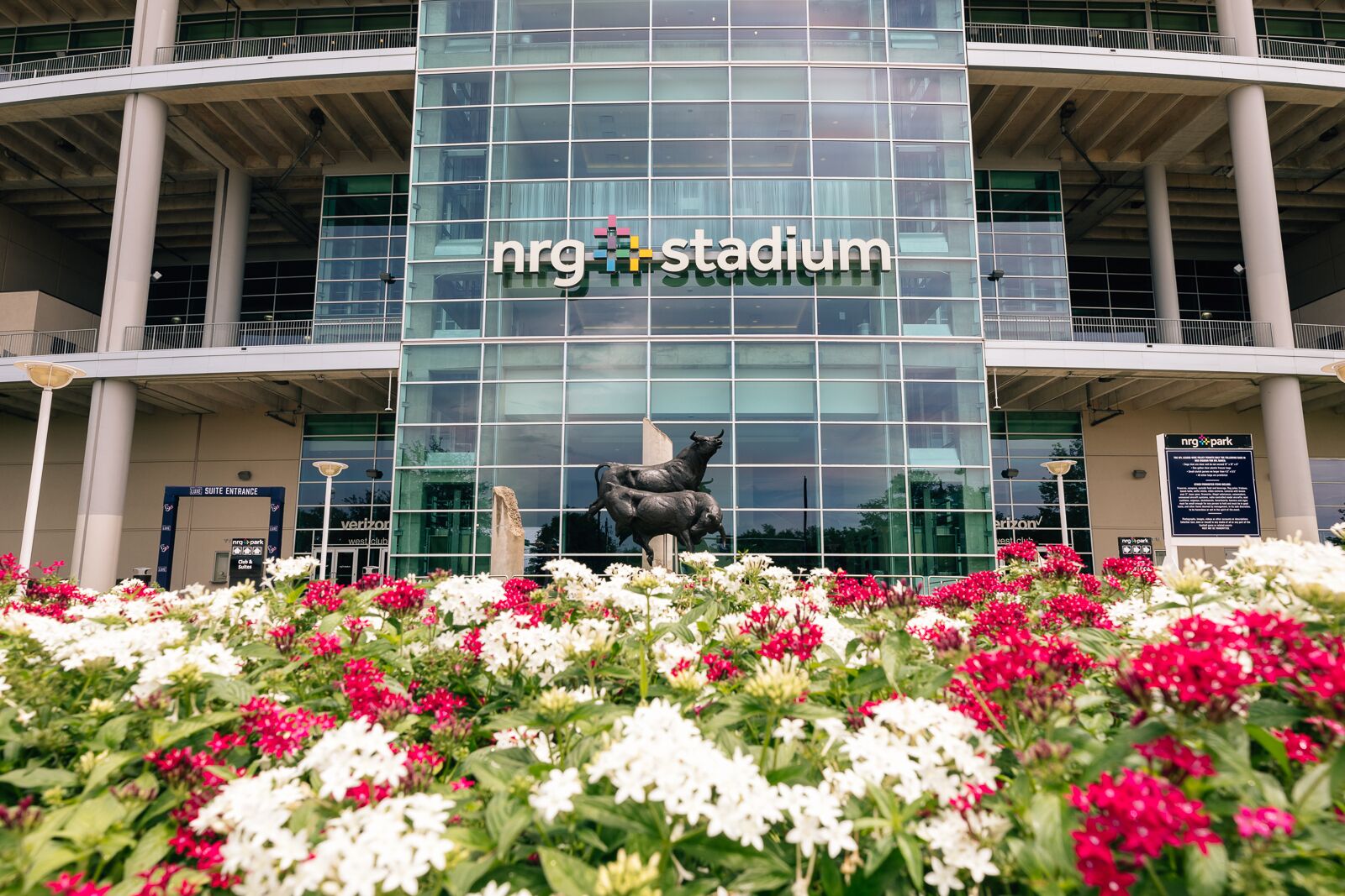 A modern building with a glass facade and a sculpture of bulls in front.