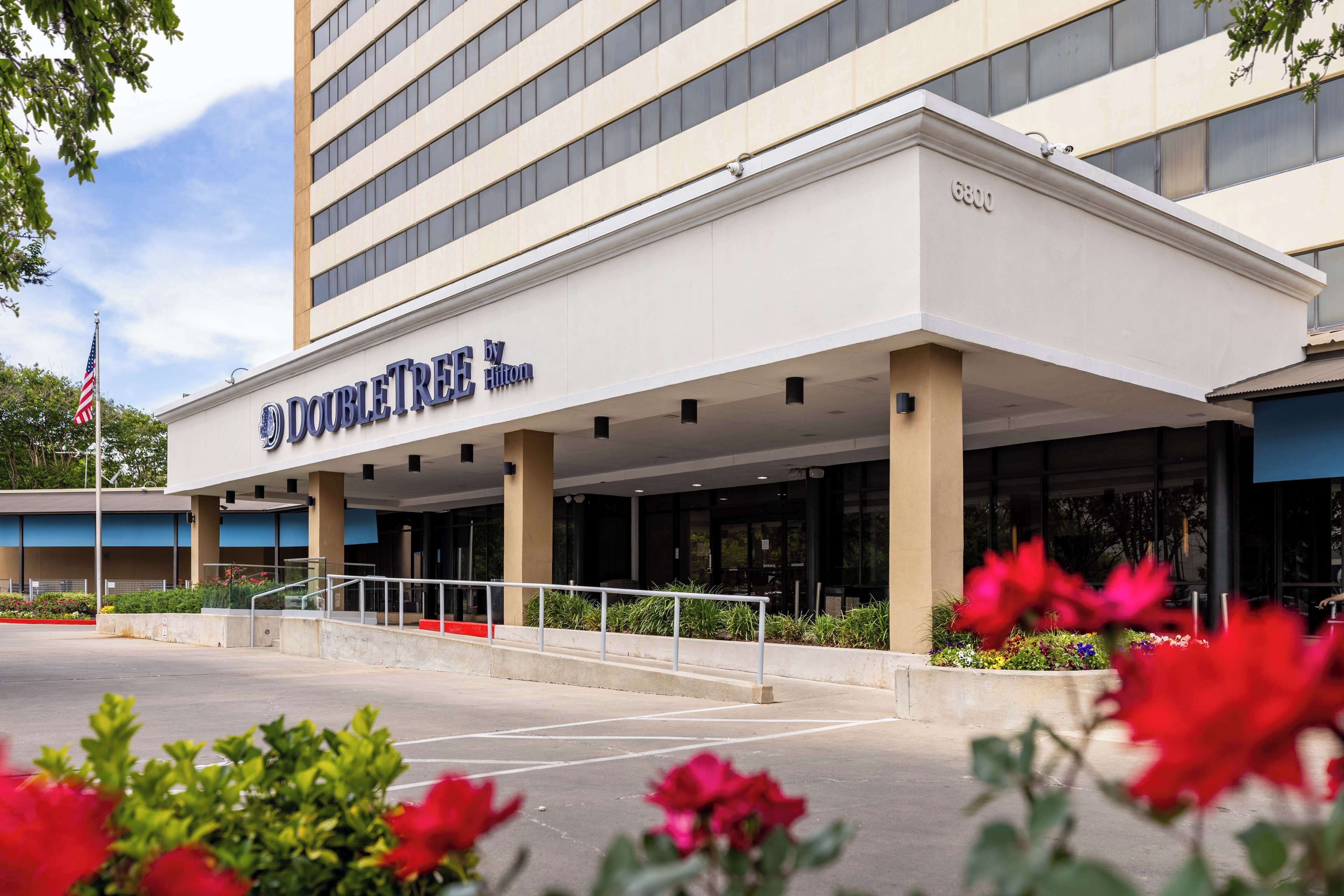 Exterior de un hotel DoubleTree con diseño moderno, que cuenta con una entrada amplia y una bandera.
