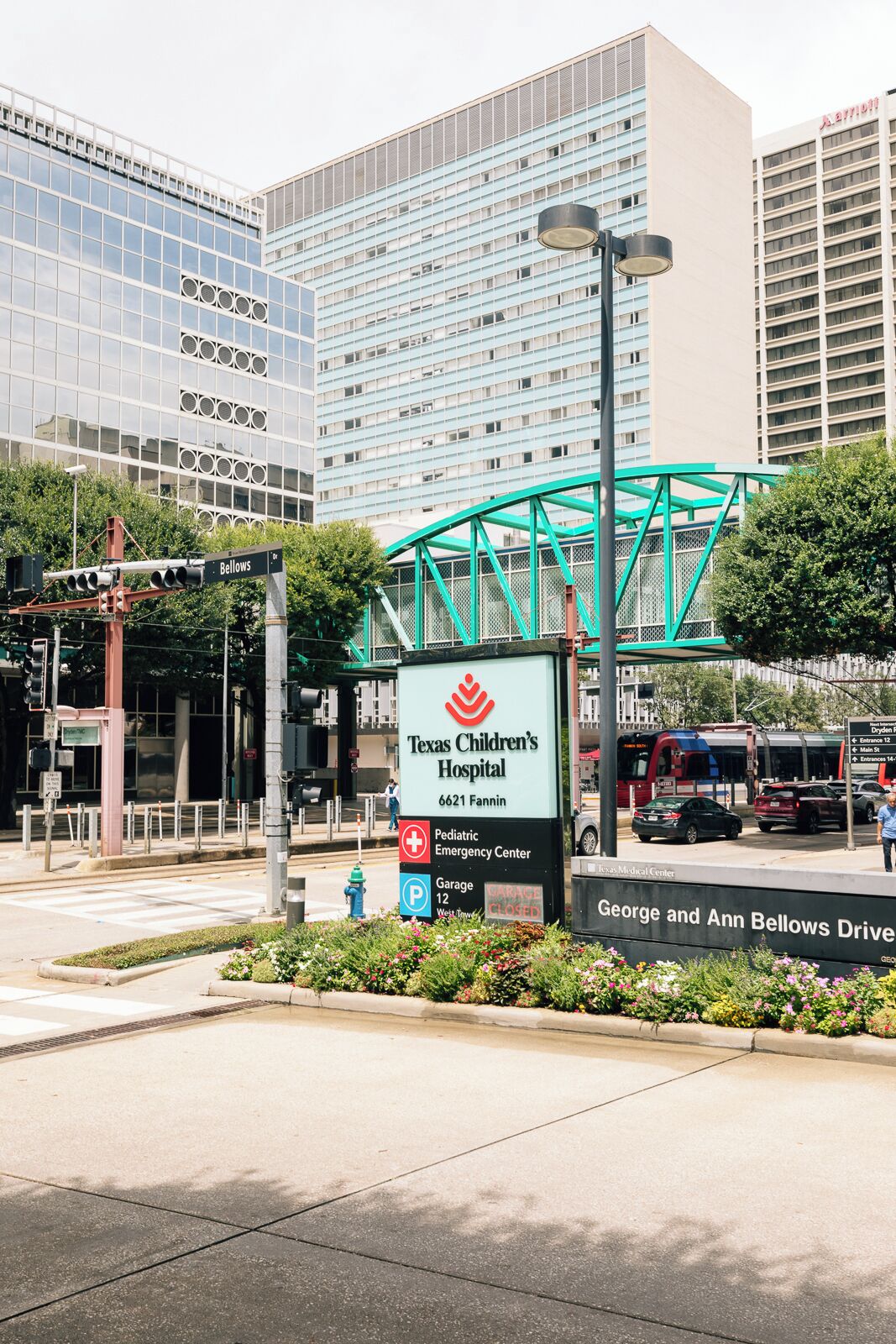 A sign for Texas Children's Hospital with a green bridge structure in the background.