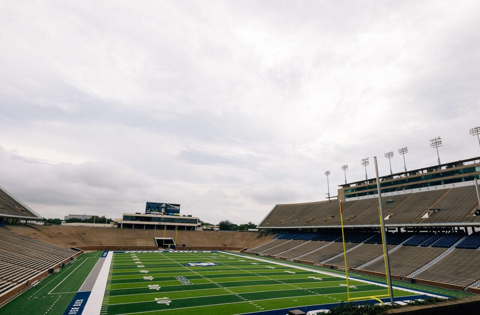 A football stadium with tiered seating, a scoreboard, and a track field.