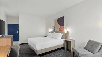 Habitación de hotel con cama, mesitas de noche, escritorio, silla y televisor.