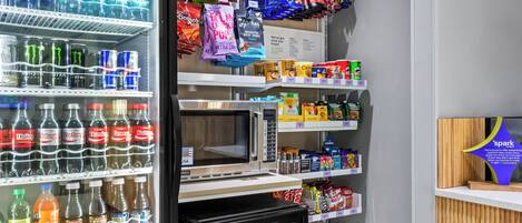 Un distributeur automatique rempli de boissons et d’en-cas, notamment de l’eau en bouteille, des sodas et divers aliments emballés.