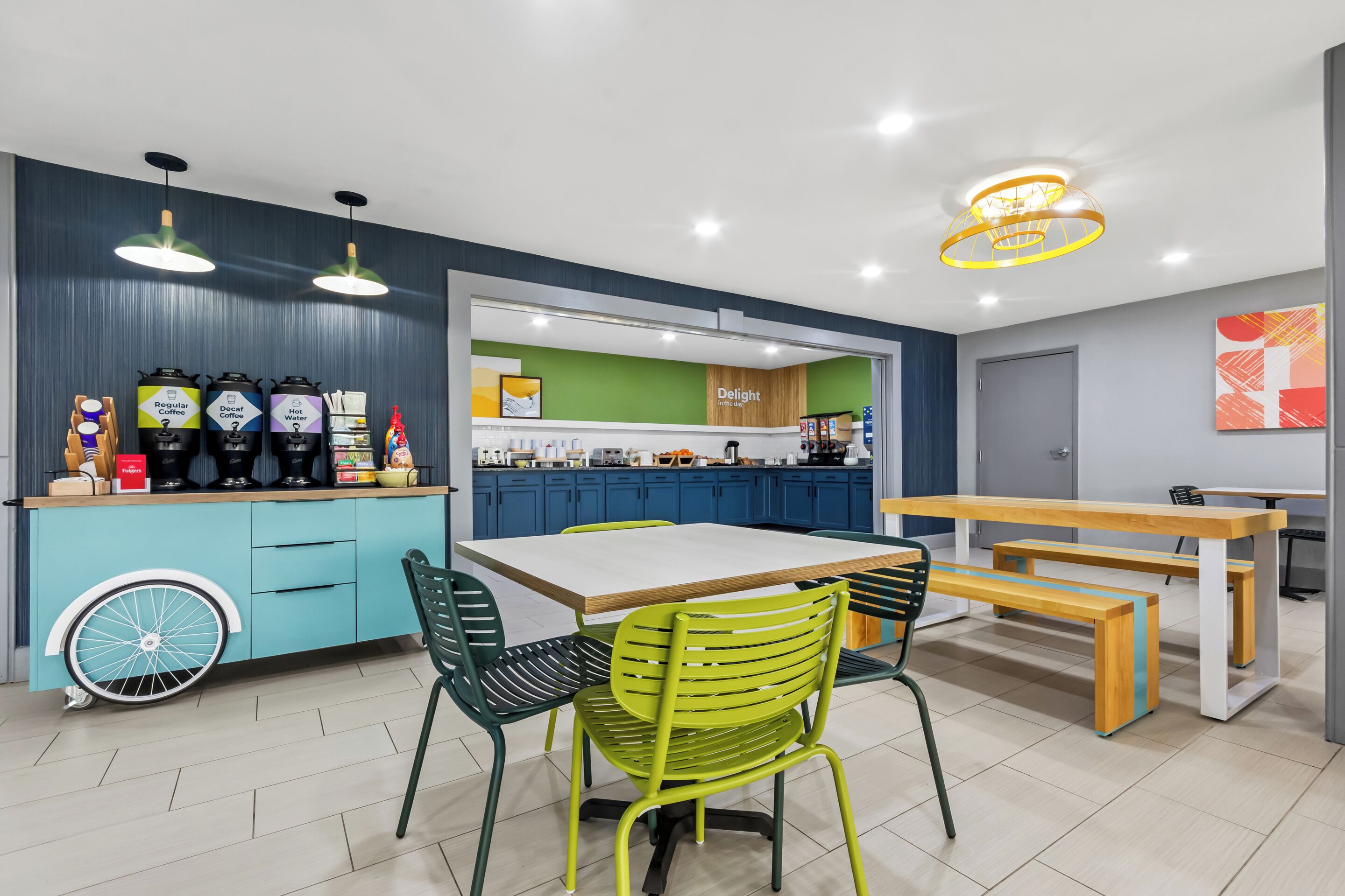 A modern kitchen with blue cabinets, a coffee station, and a dining area with a table and chairs.