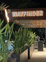 Entrada de un edificio con un letrero que dice "WAYFINDER" y un diseño moderno con listones verticales de madera.