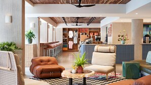 A spacious lobby with leather seating, a central wooden table with a plant, and a checkered floor. - Wayfinder Waikiki (Honolulu)