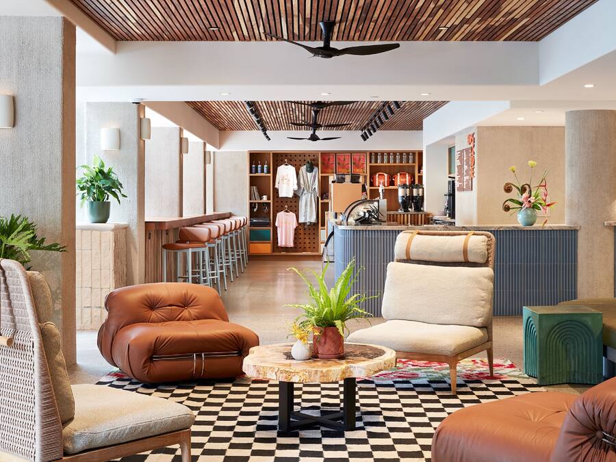 Un hall amplio con asientos de cuero, una mesa de madera central con una planta y un suelo de cuadros.