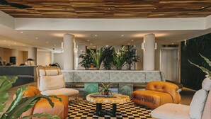A lobby with a checkered floor, a round table with a plant, and leather armchairs. - Wayfinder Waikiki (Honolulu)